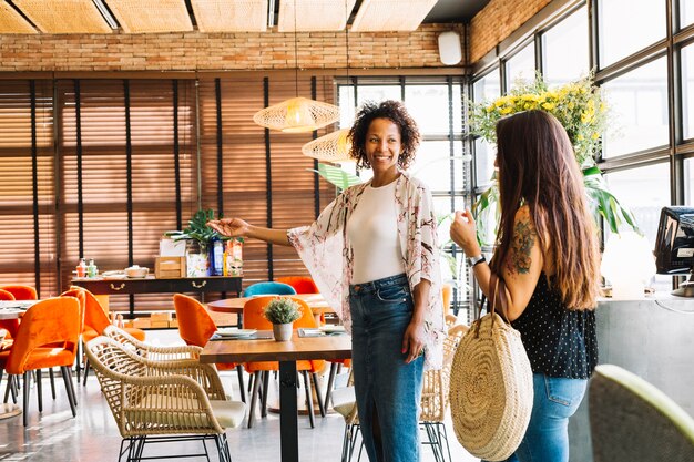 Heureuse jeune femme accueillant une clientèle féminine au restaurant