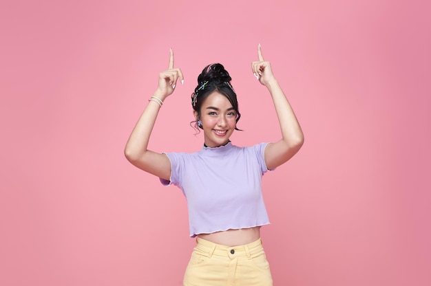 Heureuse Jeune Femme Adolescente Asiatique Debout Avec Son Doigt Pointé Isolé Sur Fond Rose