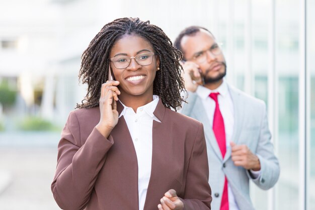 Heureuse jeune femme d'affaires parlant sur cellule