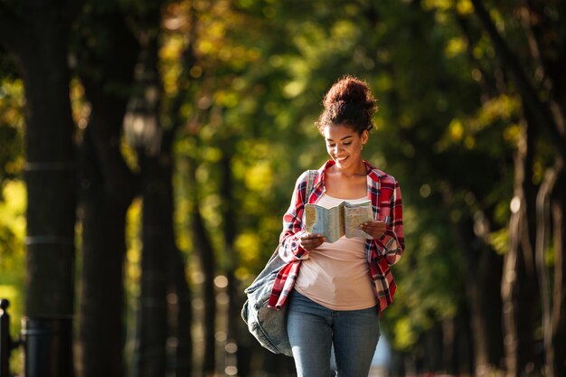 Heureuse jeune femme africaine marchant à l'extérieur dans le parc