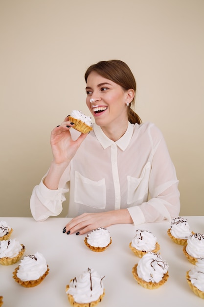 Heureuse jeune femme amusante souriant et mangeant des gâteaux