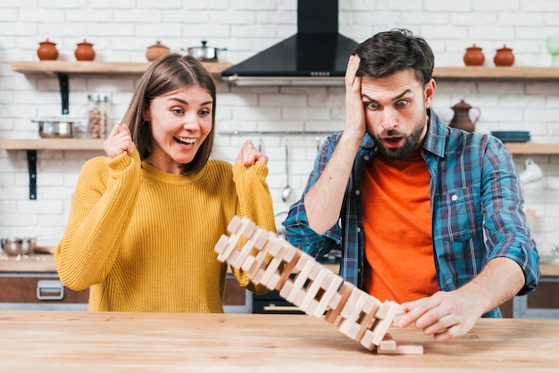 Photo gratuite heureuse jeune femme applaudir après l'effondrement de la tour de blocs de bois