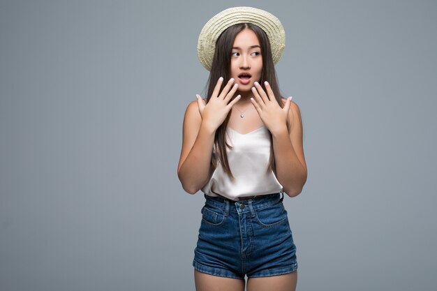 Heureuse jeune femme asiatique choquée isolée sur fond gris