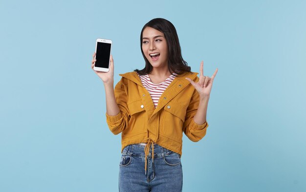 Heureuse jeune femme asiatique montrant au téléphone mobile à écran blanc isolé sur fond bleu