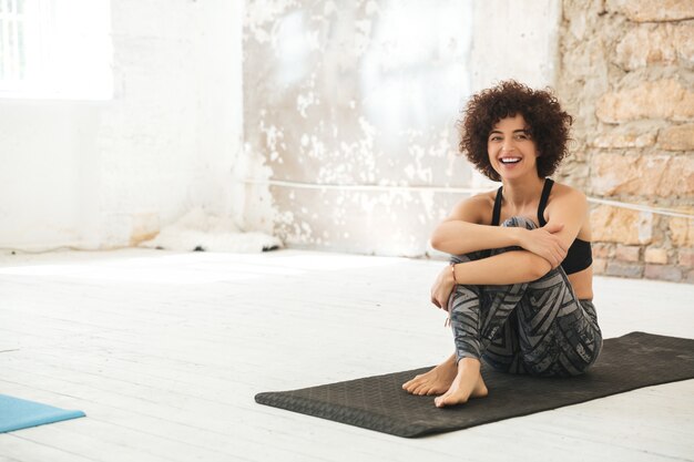 Heureuse jeune femme assise dans un studio de yoga