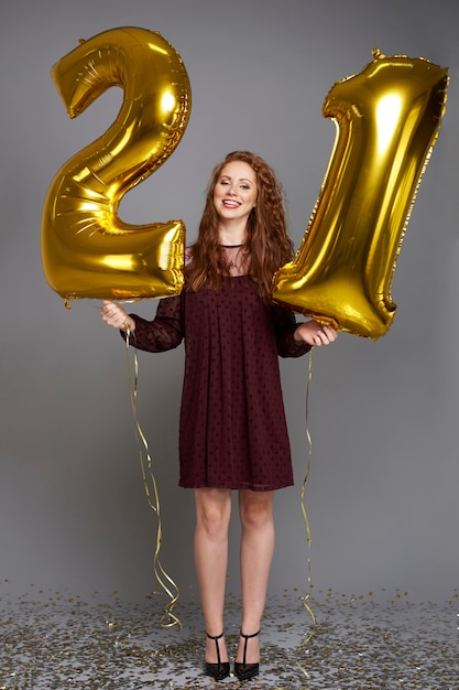 Heureuse jeune femme avec des ballons dorés célébrant son anniversaire