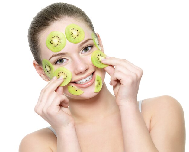 Heureuse jeune femme belle avec un masque de kiwi aux fruits sur un visage isolé sur blanc