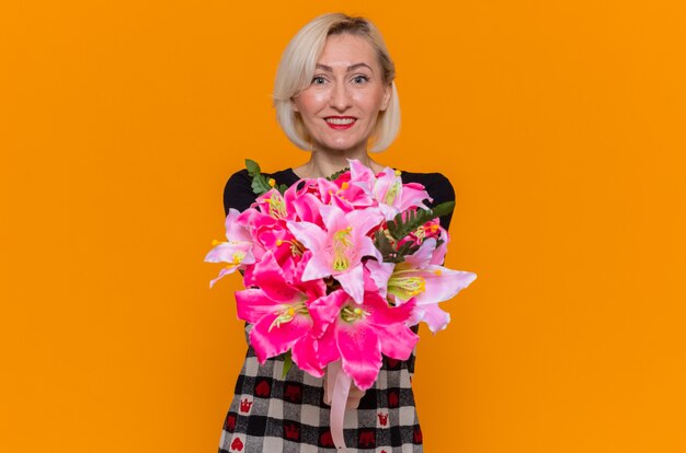 Heureuse jeune femme en belle robe tenant le bouquet de fleurs