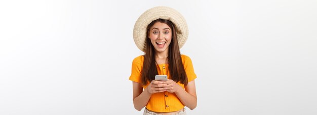 Heureuse jeune femme caucasienne à l'aide de smartphone debout isolé sur blanc