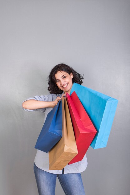 Heureuse jeune femme en chemise avec des sacs à provisions