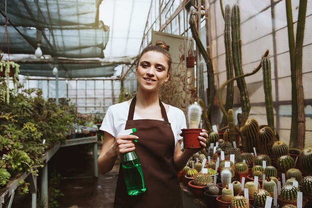 Heureuse jeune femme debout dans une serre près des plantes