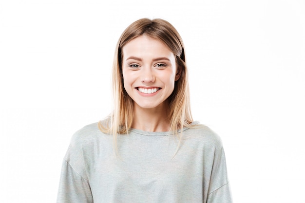 Heureuse jeune femme debout isolé sur mur blanc