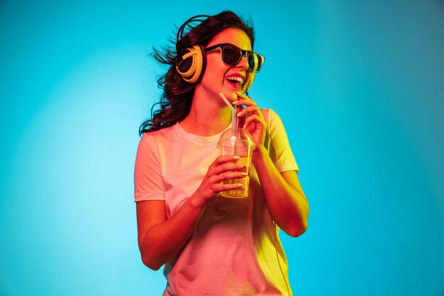 Heureuse jeune femme debout et souriant contre le bleu