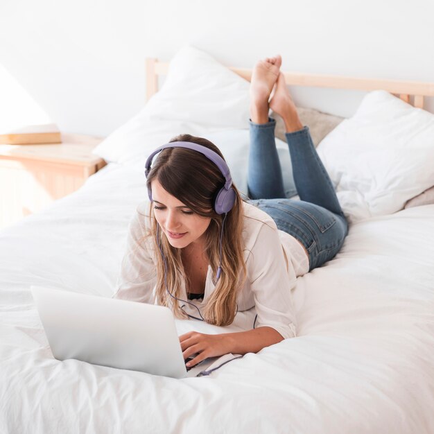 Heureuse jeune femme écoutant de la musique sur le lit