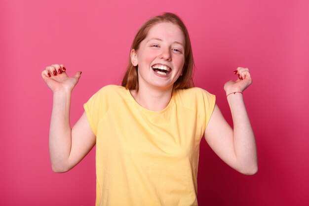 heureuse jeune femme émotionnelle en t-shirt jaune vif rire sincèrement, garde les mains levées, entend une blague drôle, aime passer du temps et s'amuser avec ses amis. Concept d'émotions de personnes