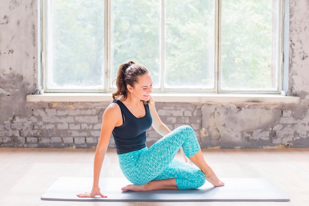 Heureuse jeune femme exerçant sur un tapis d&#39;exercice