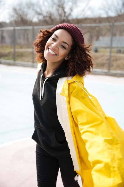 Heureuse Jeune Femme Frisée Africaine Portant Un Manteau Jaune