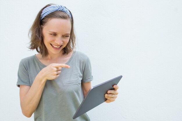 Heureuse jeune femme joyeuse à l'aide de la tablette pour la conversation vidéo