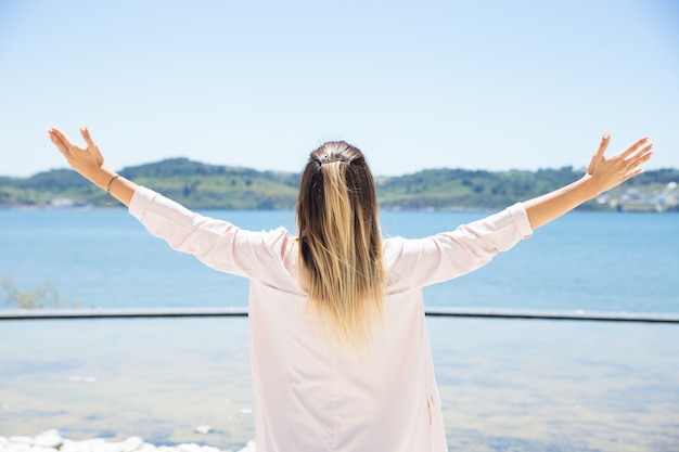 Heureuse jeune femme ouvrant les bras au paysage