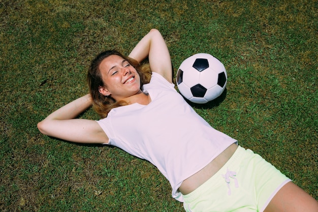 Heureuse jeune femme près du ballon sur l&#39;herbe