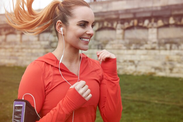 Heureuse jeune femme qui court à l'extérieur. La course est un excellent cardio du matin