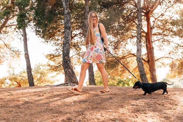 Heureuse jeune femme se promener avec son animal de compagnie dans le parc