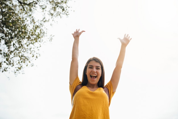 Heureuse jeune femme avec ses mains en vue de faible angle