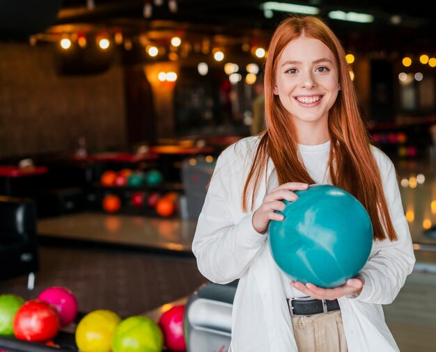 Heureuse jeune femme tenant une boule de bowling turquoise