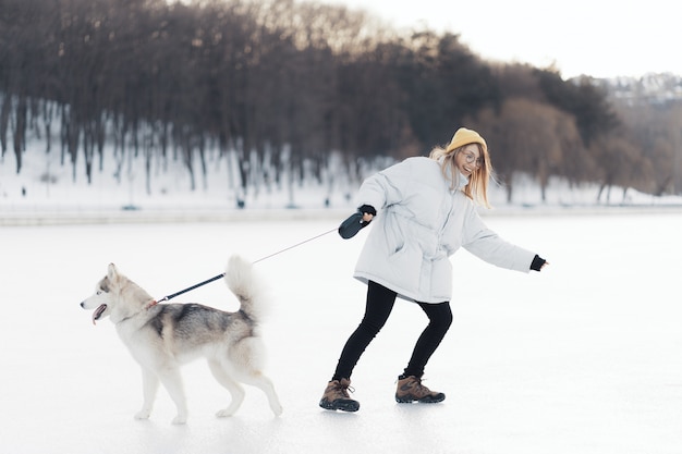 Heureuse jeune fille jouant avec un chien husky sibérien à Winter Park
