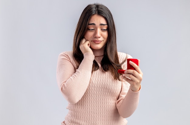 Heureuse jeune fille le jour de la Saint-Valentin tenant et regardant la bague de mariage isolée sur fond blanc