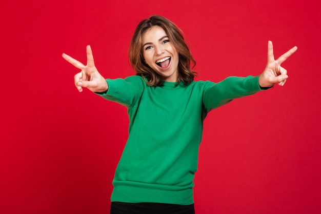 Heureuse jeune jolie femme montrant le geste de paix.