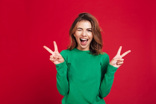 Heureuse jeune jolie femme montrant le geste de paix.