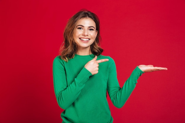 Heureuse jeune jolie femme montrant la surface pointant.