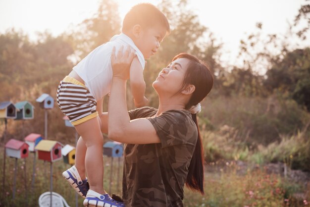 Heureuse jeune maman joue et s&#39;amuse avec son petit bébé dans le parc par une journée d&#39;été ensoleillée