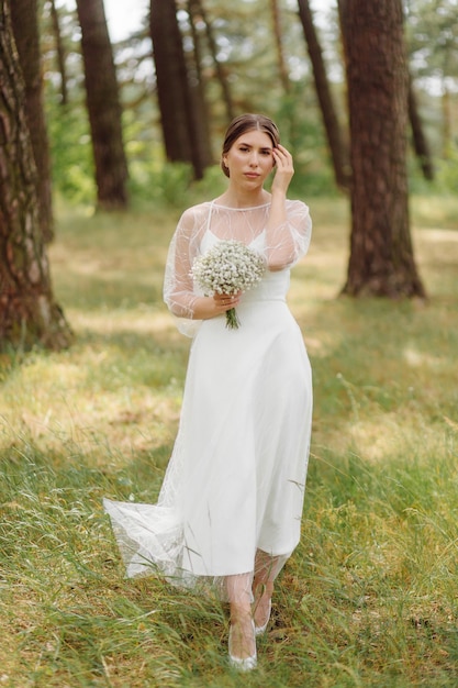 Heureuse jeune mariée dans une robe de mariée blanche de forêt de pins