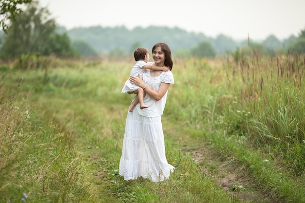 Heureuse jeune mère avec un tout-petit dans les bras marchant