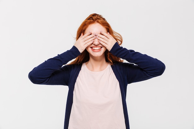 Photo gratuite heureuse jeune rousse couvrant les yeux avec les mains.