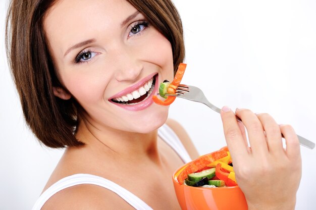 Heureuse jolie femme mange une salade de légumes