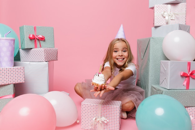 Heureuse jolie petite fille dans un chapeau d'anniversaire célébrant