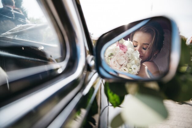 Heureuse mariée renifle des fleurs dans la voiture