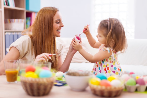 Heureuse mère aidant bébé à peindre sur les oeufs de Pâques