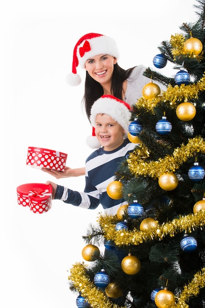 Heureuse mère avec enfant calez la boîte avec un cadeau près de l'arbre de Noël