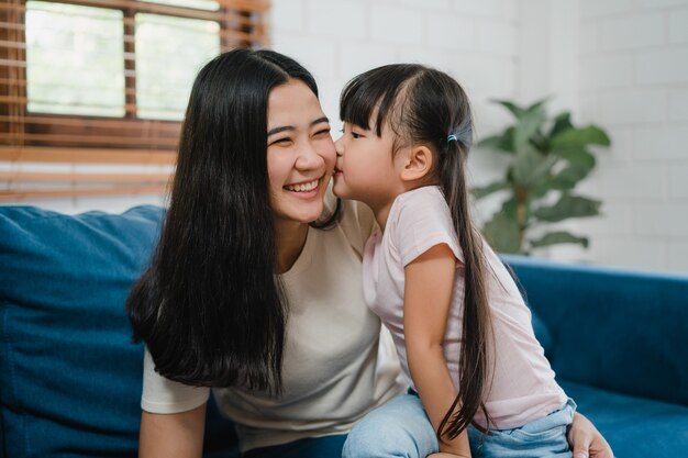 Heureuse mère de famille asiatique et fille embrassant s'embrasser sur la joue félicitant avec anniversaire à la maison.