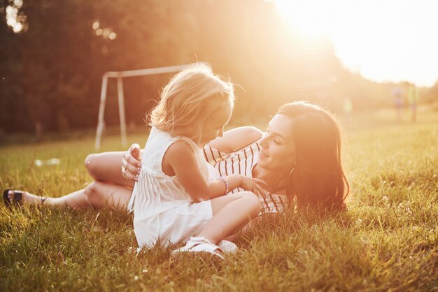 Heureuse mère et fille étreignant dans un parc au soleil sur un été lumineux d'herbes.