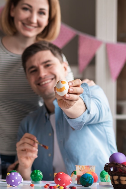 Heureuse mère et père montrant des oeufs peints pour Pâques