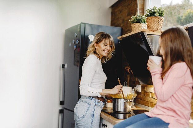 Heureuse mère préparant la nourriture et communiquant avec sa fille dans la cuisine