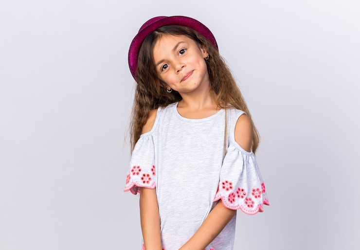 Photo gratuit heureuse petite fille caucasienne avec chapeau de fête violet isolé sur mur blanc avec espace de copie