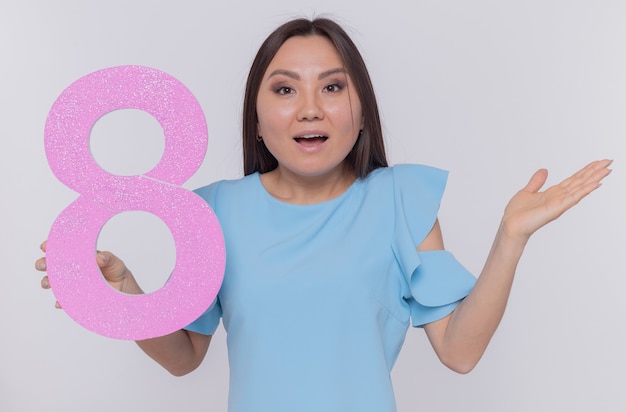 Heureuse et surprise femme asiatique tenant le numéro huit en carton