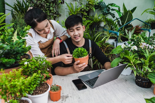 Heureusement, un couple de jardiniers utilise un ordinateur portable pendant un didacticiel en ligne sur les plans en pot en atelier ensemble