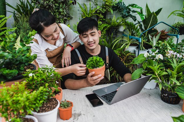 Heureusement, un couple de jardiniers utilise un ordinateur portable pendant un didacticiel en ligne sur les plans en pot en atelier ensemble